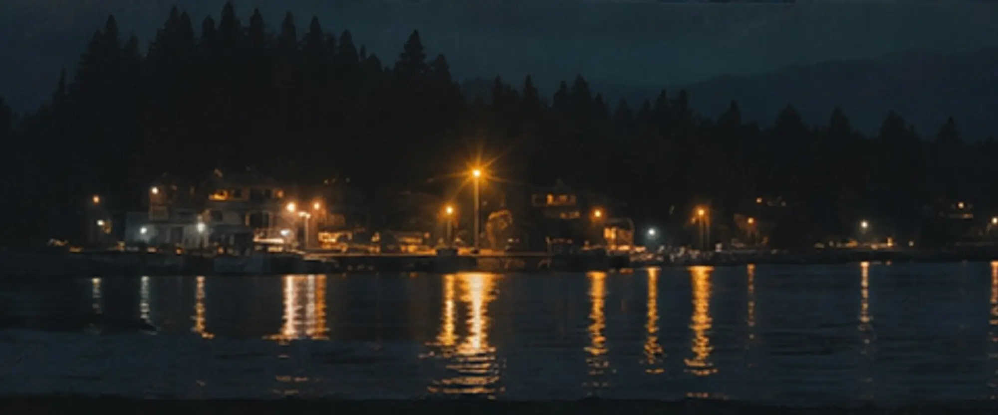 Town lights reflected across water at night