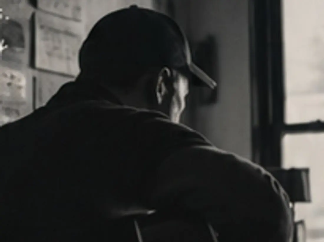 A person seen from behind at a window, notes pinned to the wall beside them